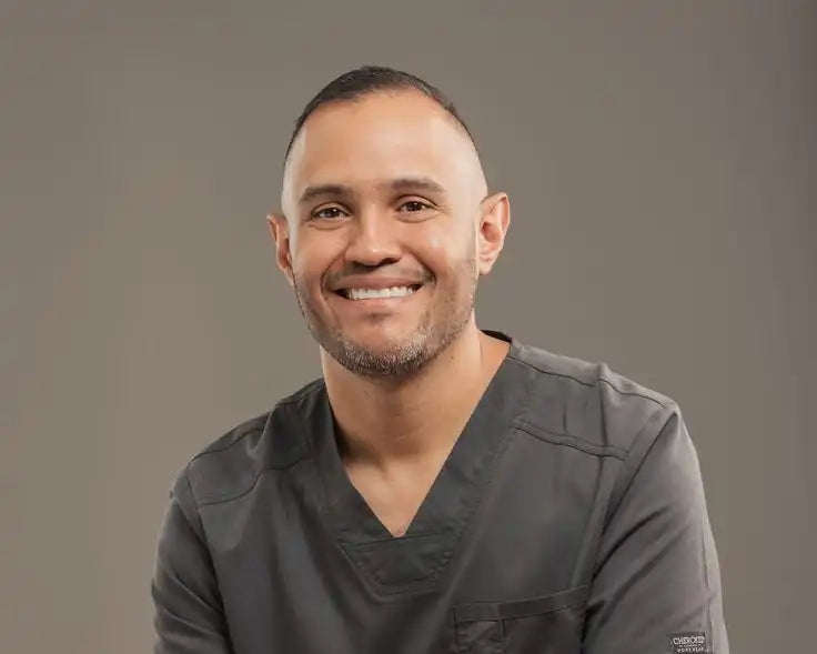 Man wearing dark gray medical scrubs against a plain background